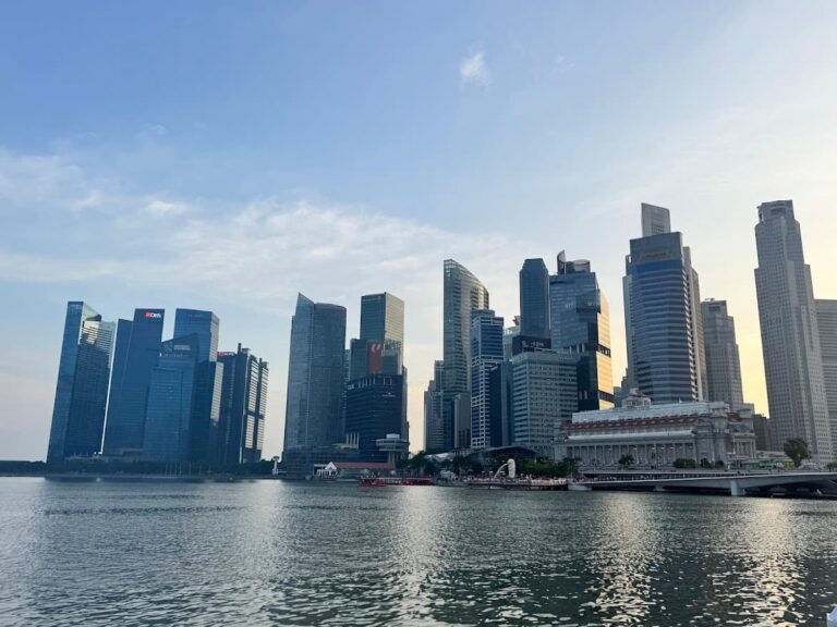 Wide view of the Singapore skyline at Marina Bay, featuring financial district skyscrapers and the Fullerton Hotel at sunset for a Singapore travel guide.