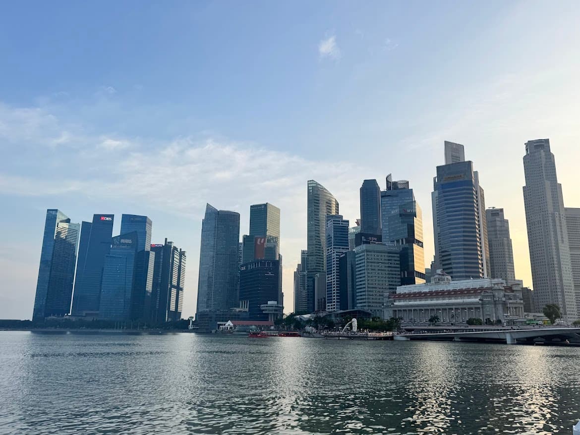 Wide view of the Singapore skyline at Marina Bay, featuring financial district skyscrapers and the Fullerton Hotel at sunset for a Singapore travel guide.