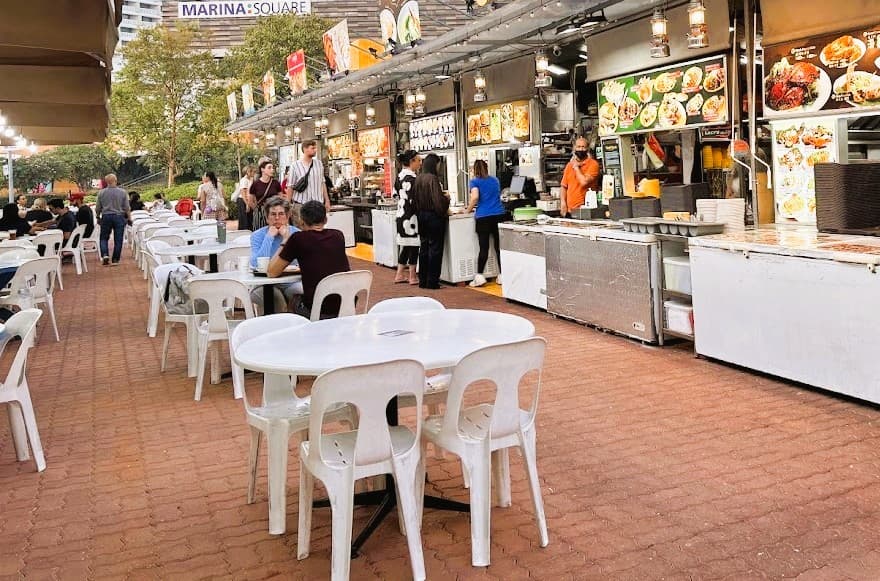 Popular Singapore hawker stalls at Gluttons Bay serving satay, sambal stingray and local seafood dishes in an open-air evening market setting.