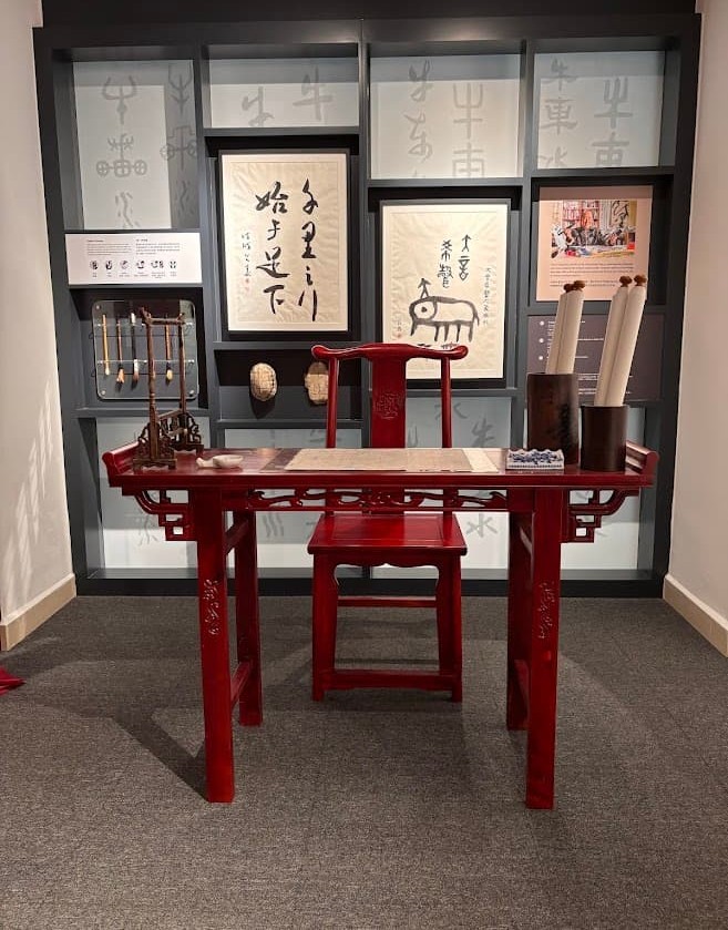 Traditional red wooden desk and chair displayed in a Chinese calligraphy exhibit