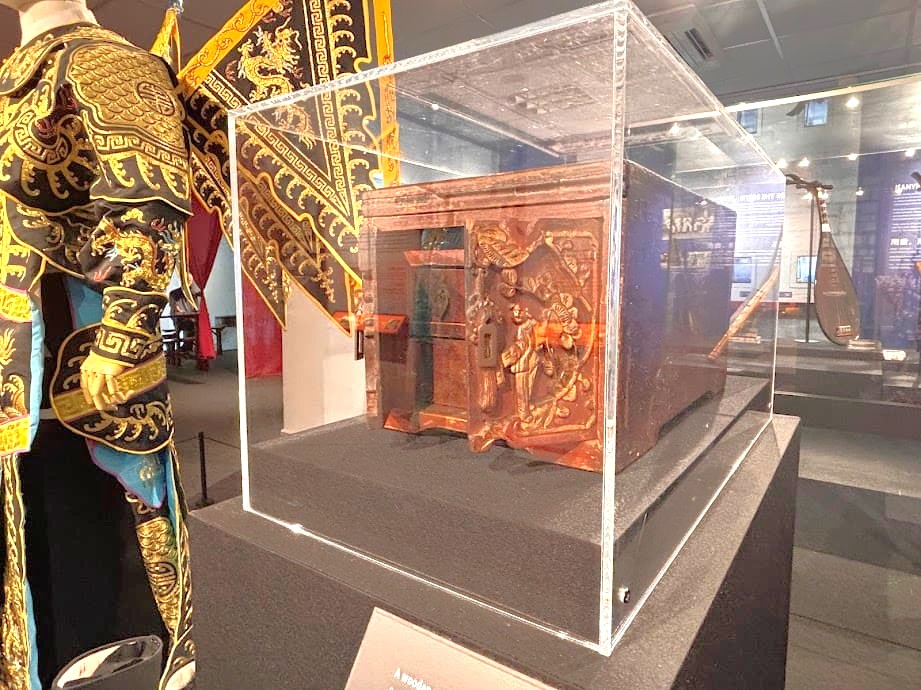 Ornate wooden make-up box used by Cantonese opera performers, displayed in a glass case