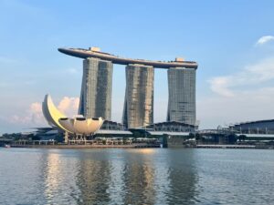 A wide shot of the Marina Bay Sands hotel and the lotus-inspired ArtScience Museum situated along the waterfront in Singapore.