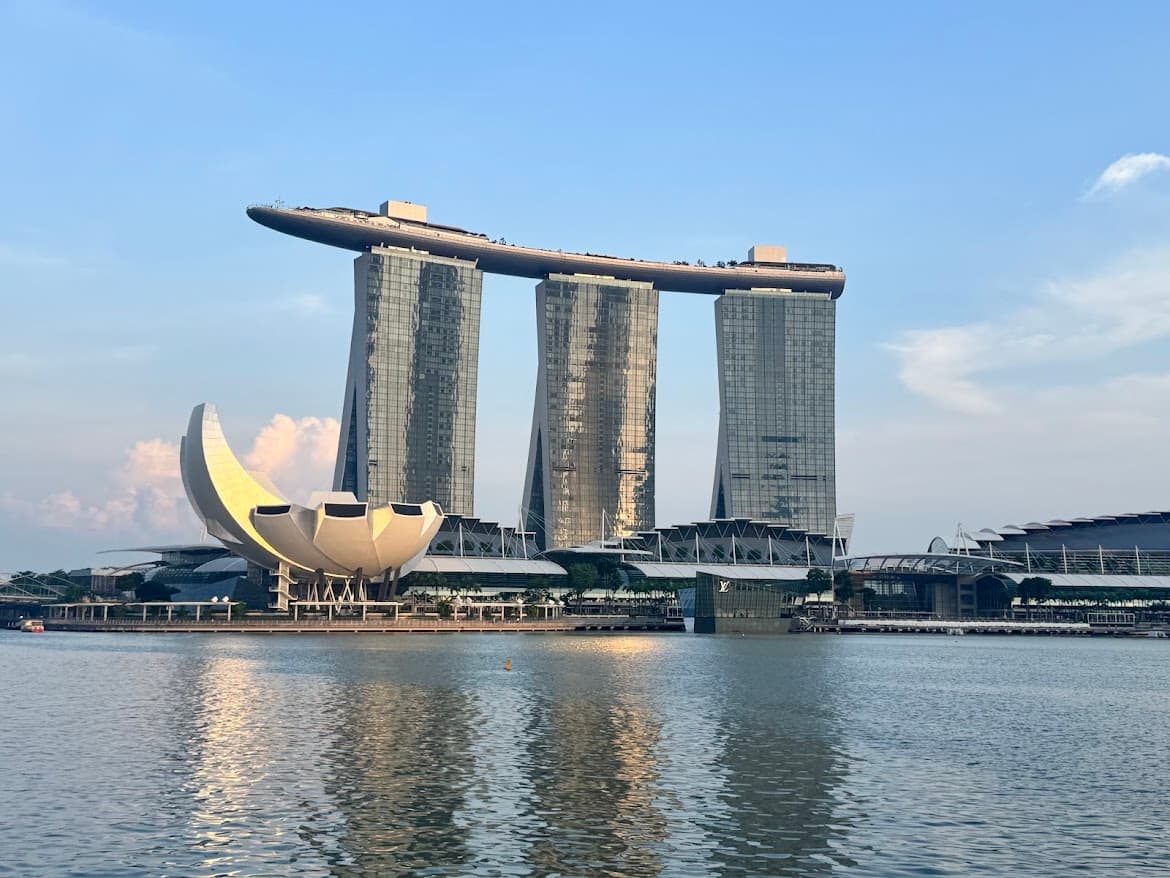 A wide shot of the Marina Bay Sands hotel and the lotus-inspired ArtScience Museum situated along the waterfront in Singapore.