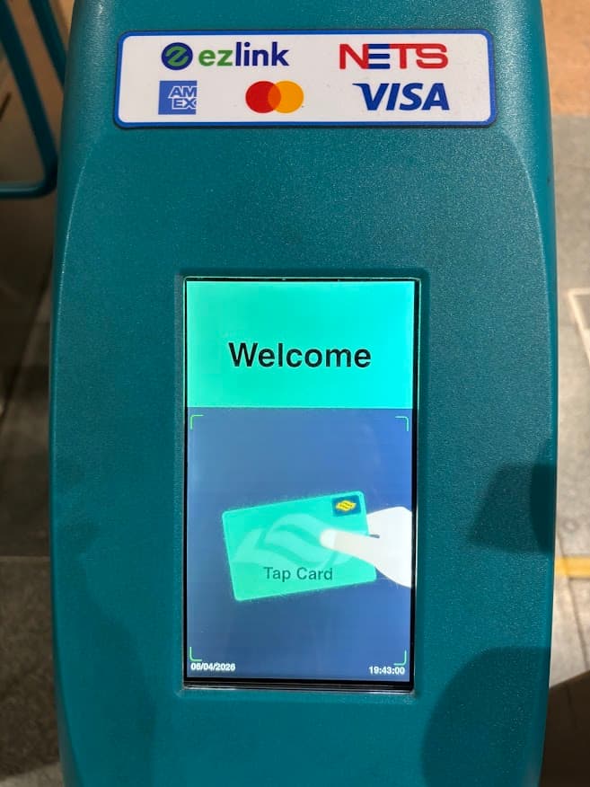 Close-up of a Singapore MRT fare gate card reader with the words "Tap Card" on the screen and logos for EZ-Link, Visa, and Mastercard.