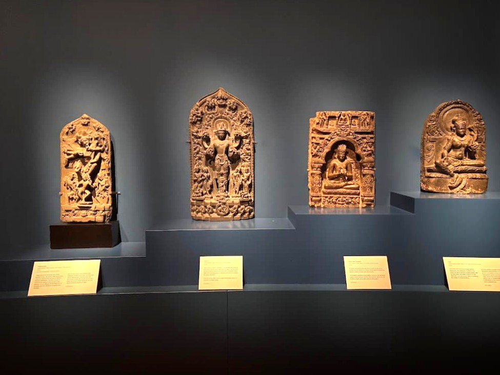 Four intricately carved stone relief panels from the Pala dynasty on display at the Asian Civilisations Museum Singapore, each depicting Hindu or Buddhist deities in ornate arched frames.