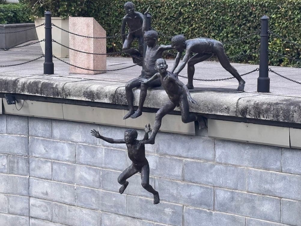 A bronze sculpture titled First Generation by Chong Fah Cheong, featuring five boys leaping into the Singapore River near Cavenagh Bridge.